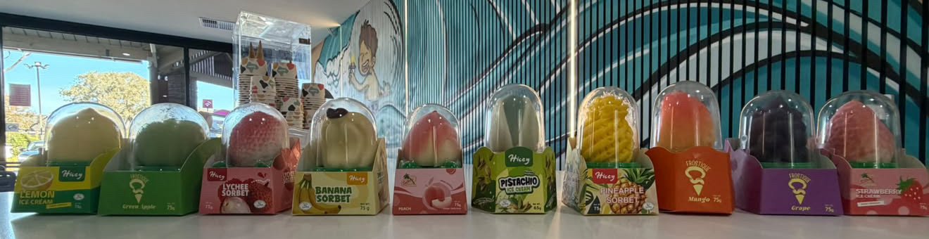 Ten fruit-shaped Viral Dubai Ice Creams in clear domes lined up on the counter, from lemon to strawberry